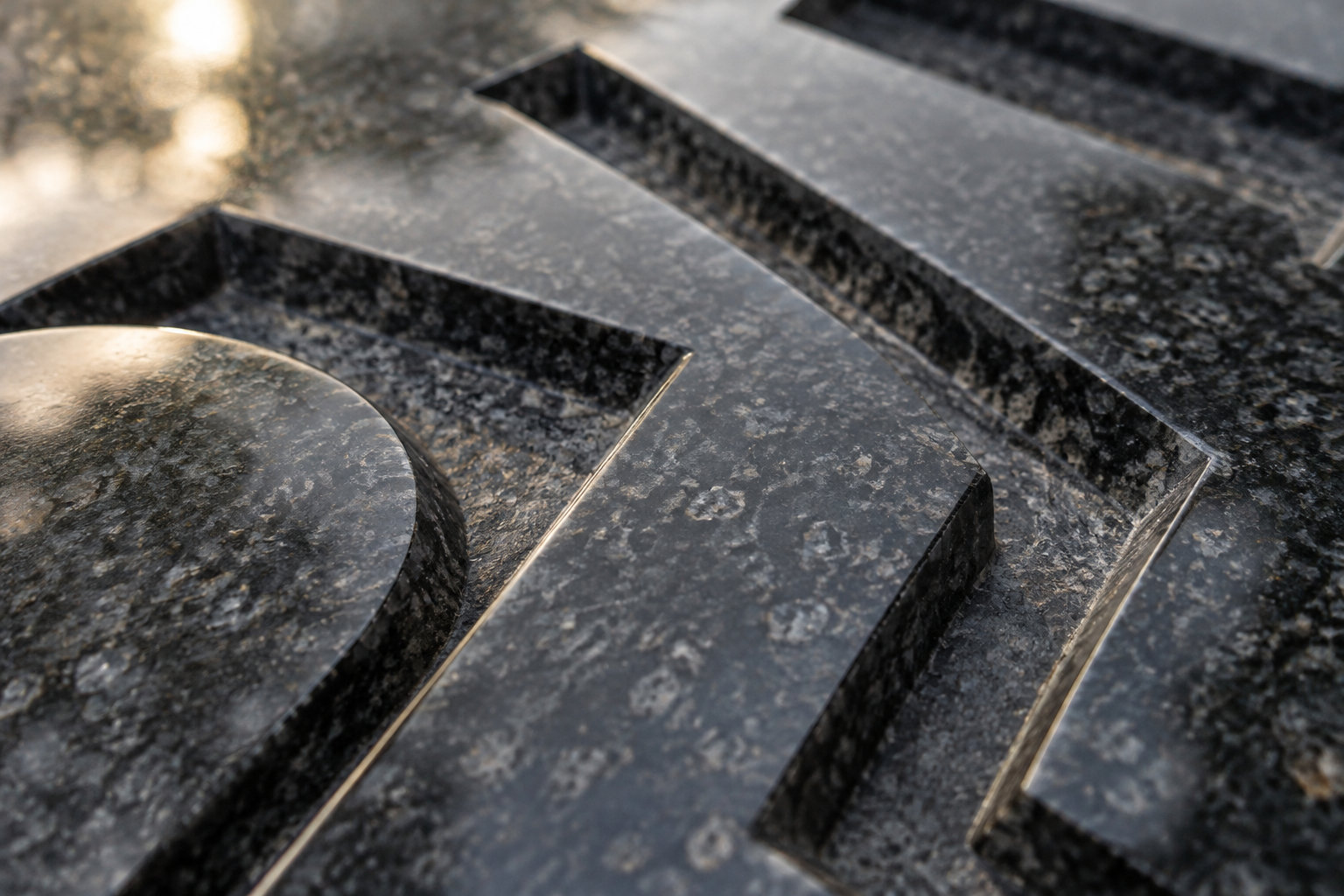Gros plan sur des lettres métalliques en relief fixées sur une surface sombre et brillante.